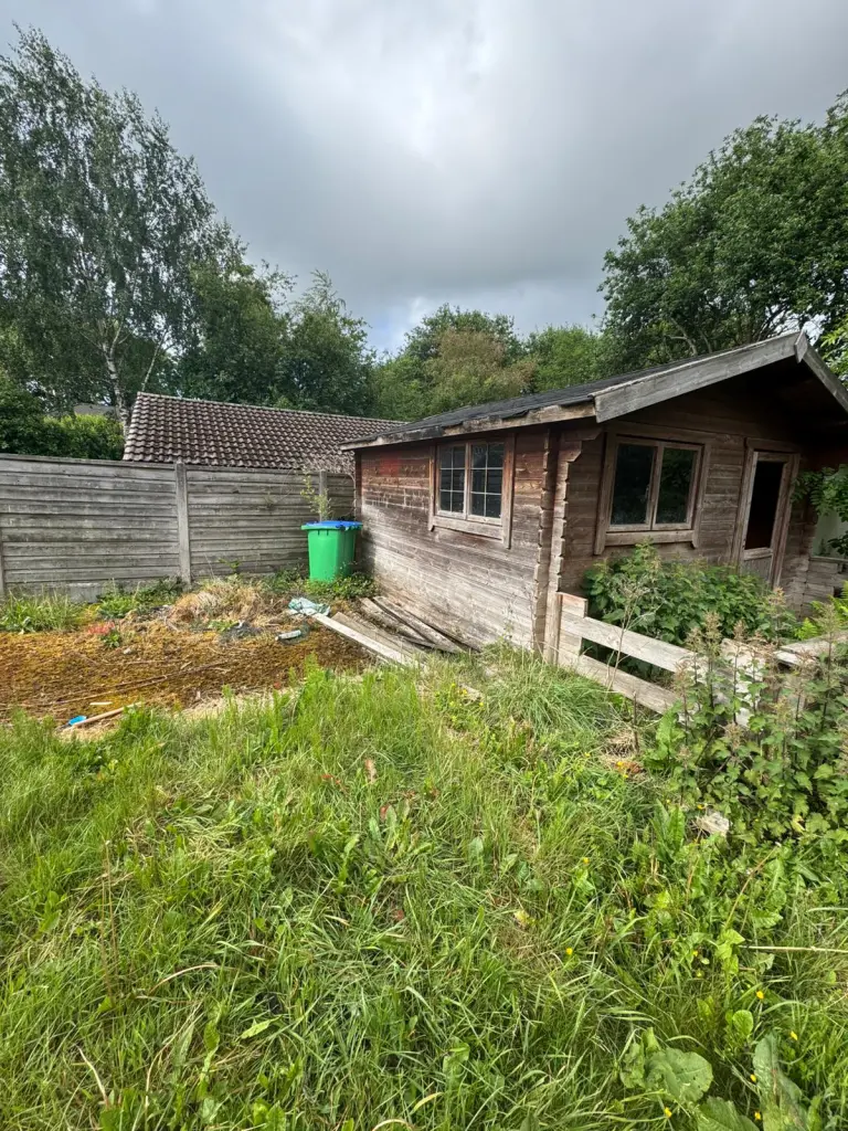 Overgrown garden and outbuildings before clearance in Heywood.