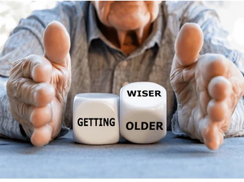Elderly hands framing dice that spell out Getting Wiser and Getting Older