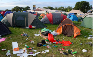 Abandoned tents with litter strewn across the grass of a festival campsite