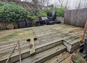 Weathered timber decking in a back garden before clearance
