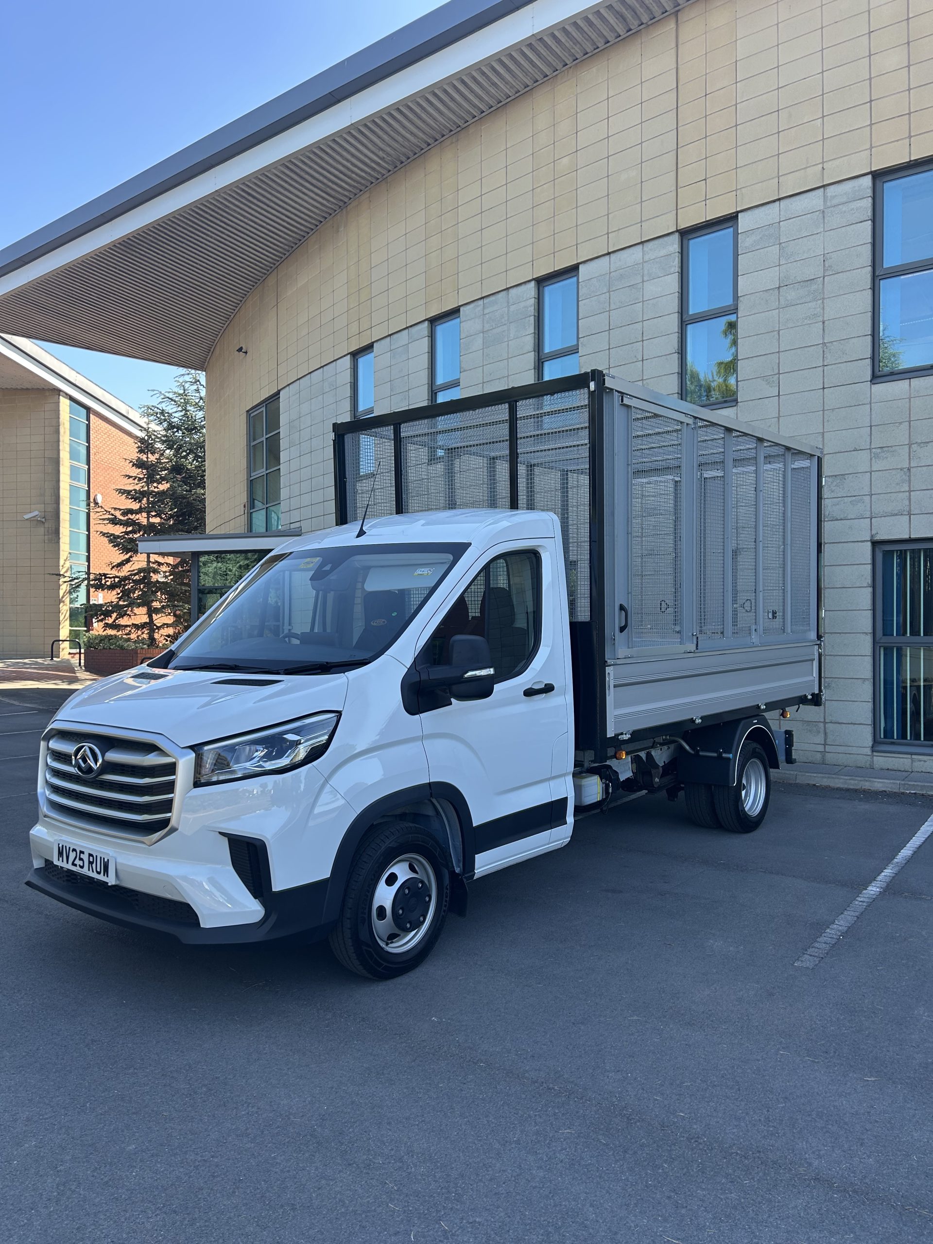 White caged tipper truck parked outside a modern office building