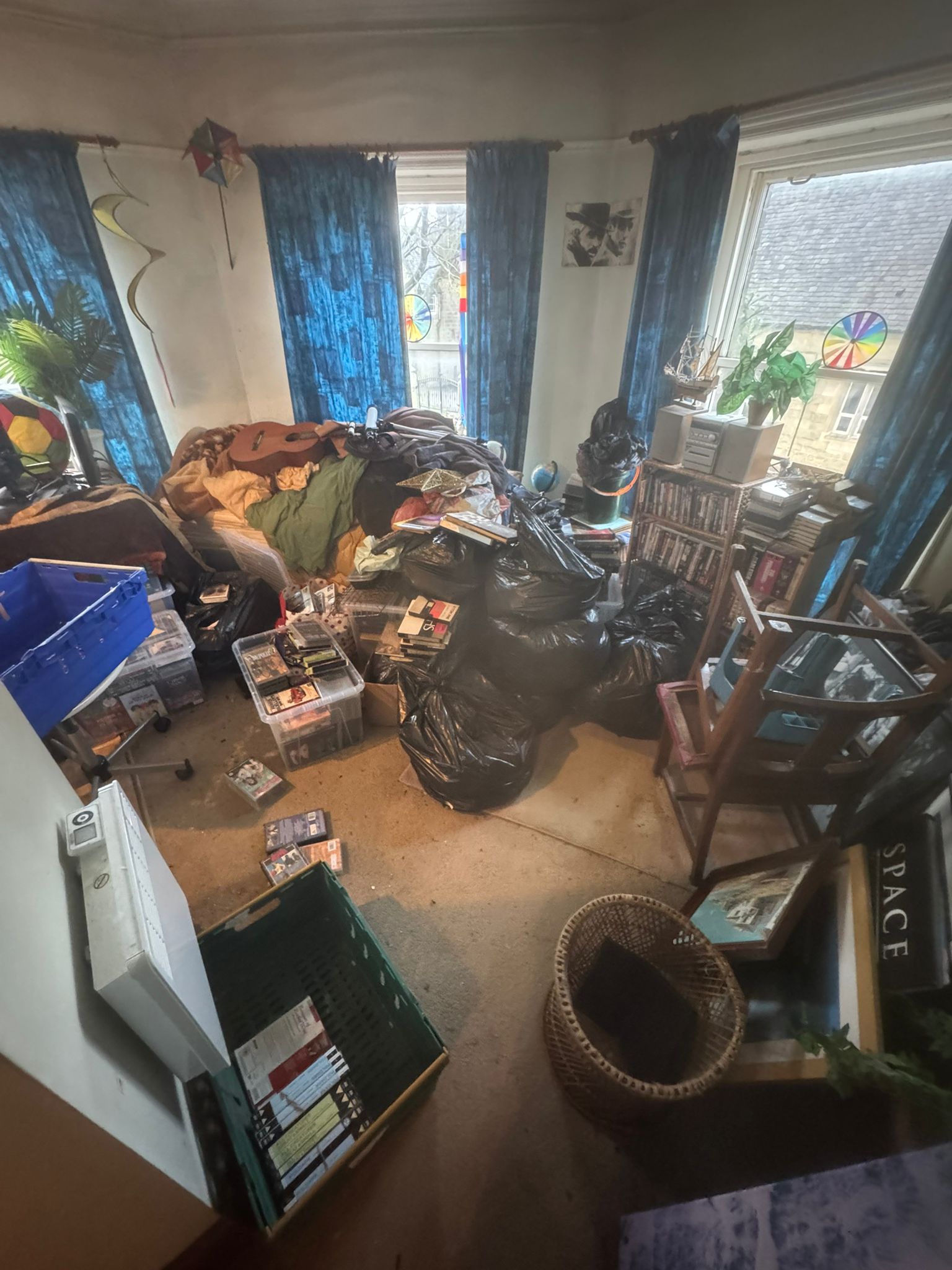 Cluttered living room filled with belongings, boxes and bags