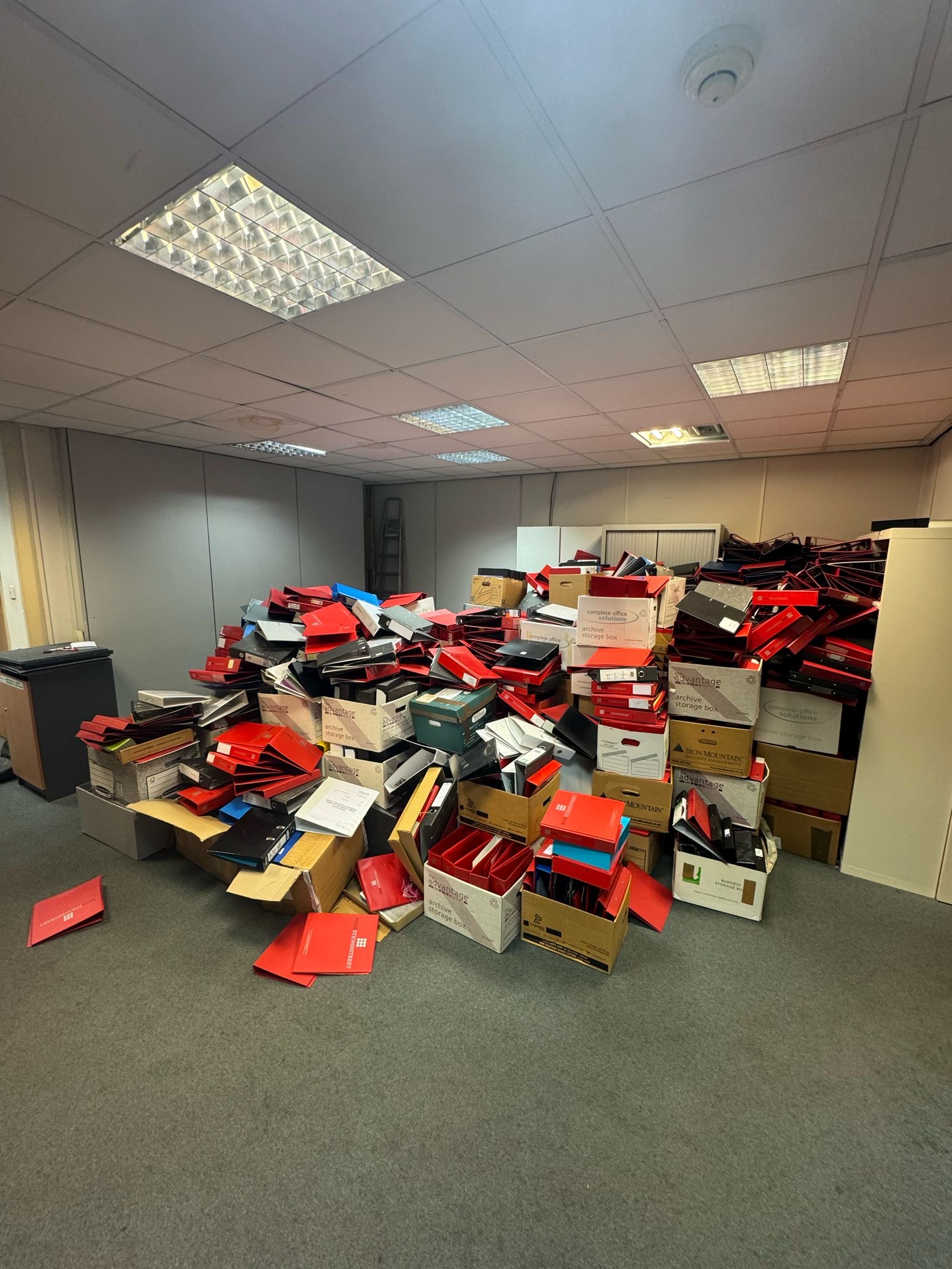 Office floor covered with discarded red and black boxes and packaging