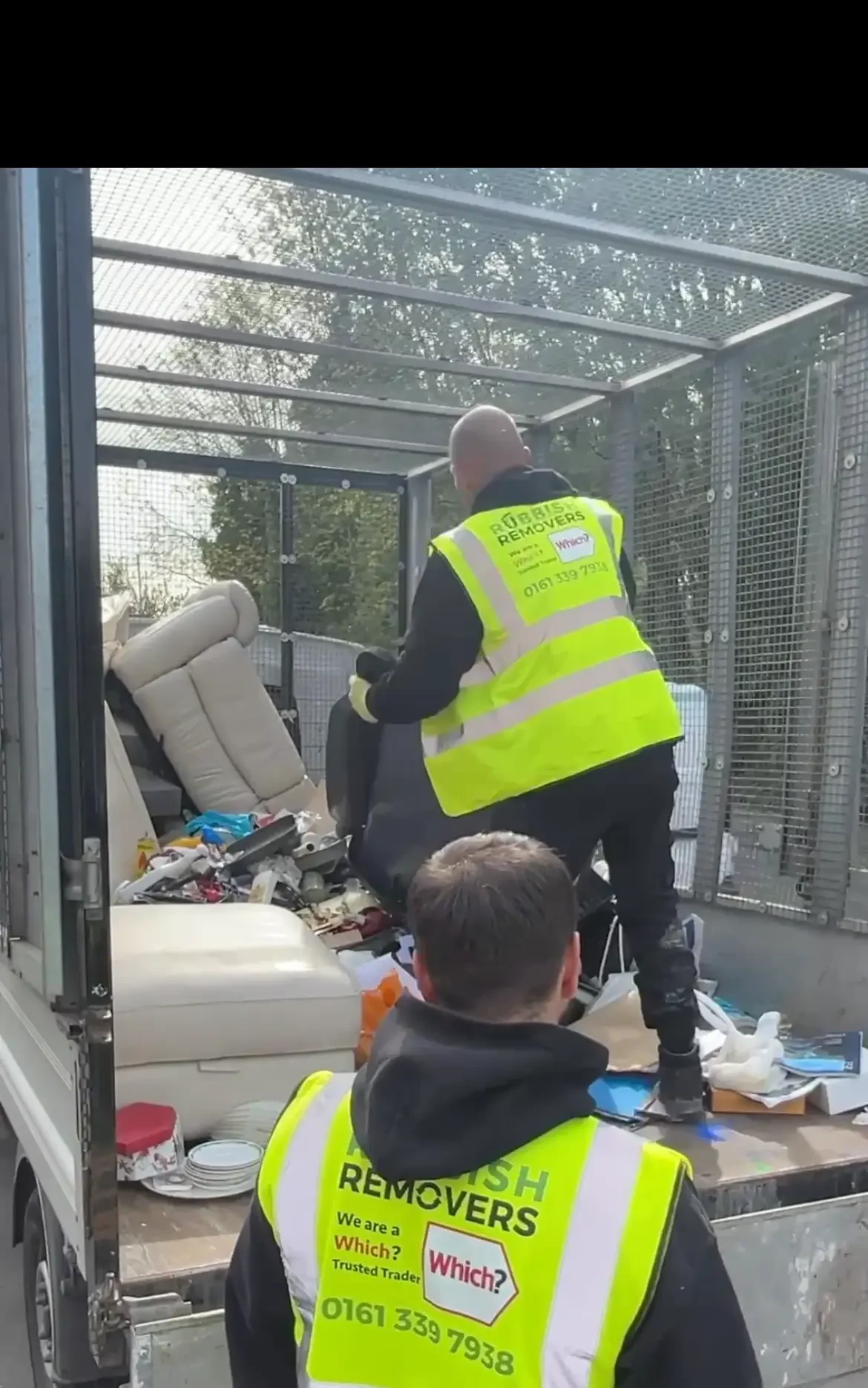 Two workers in Rubbish Removers hi-vis vests loading household waste into a caged tipper