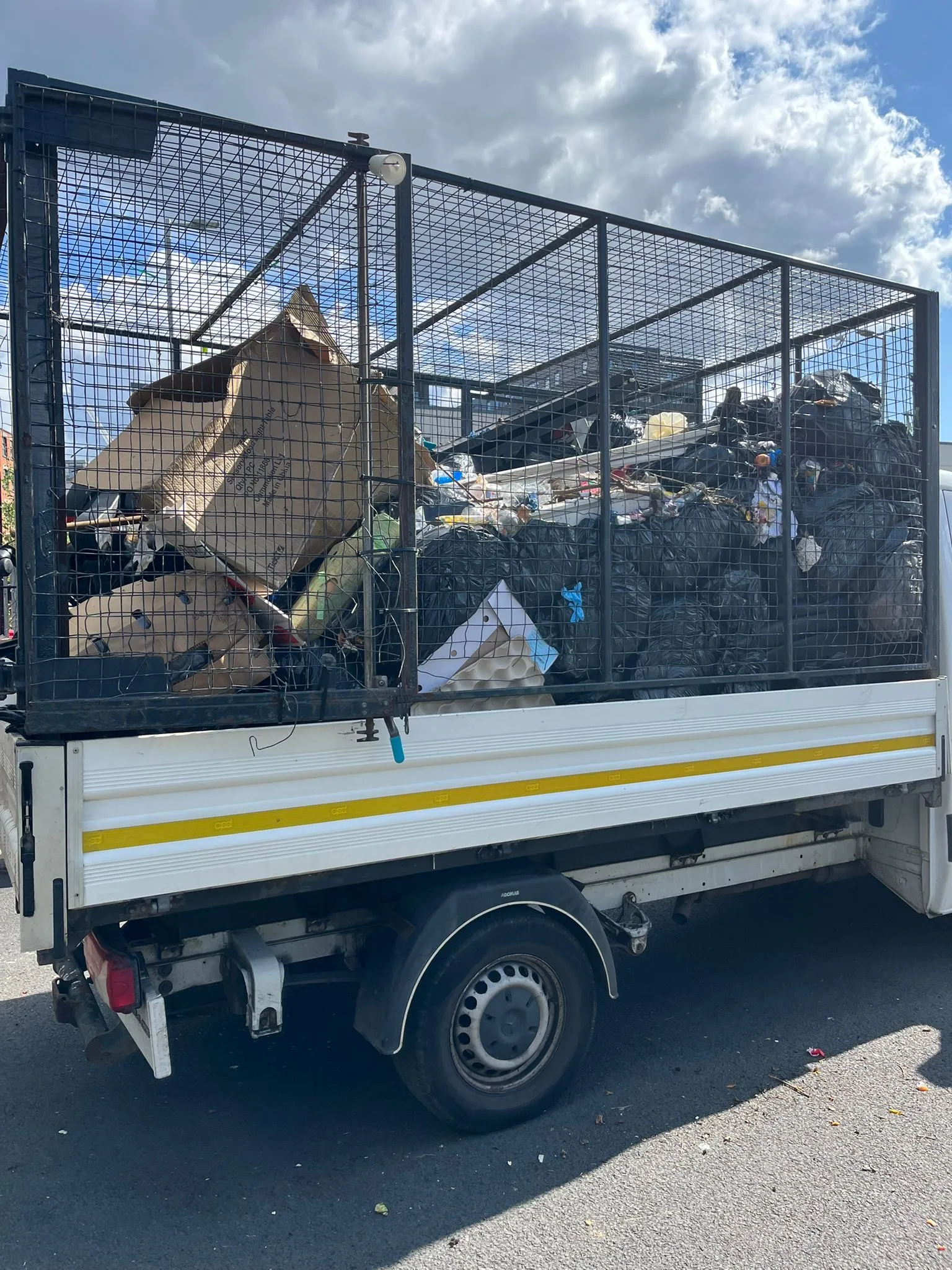 Caged tipper truck loaded high with cardboard and mixed waste