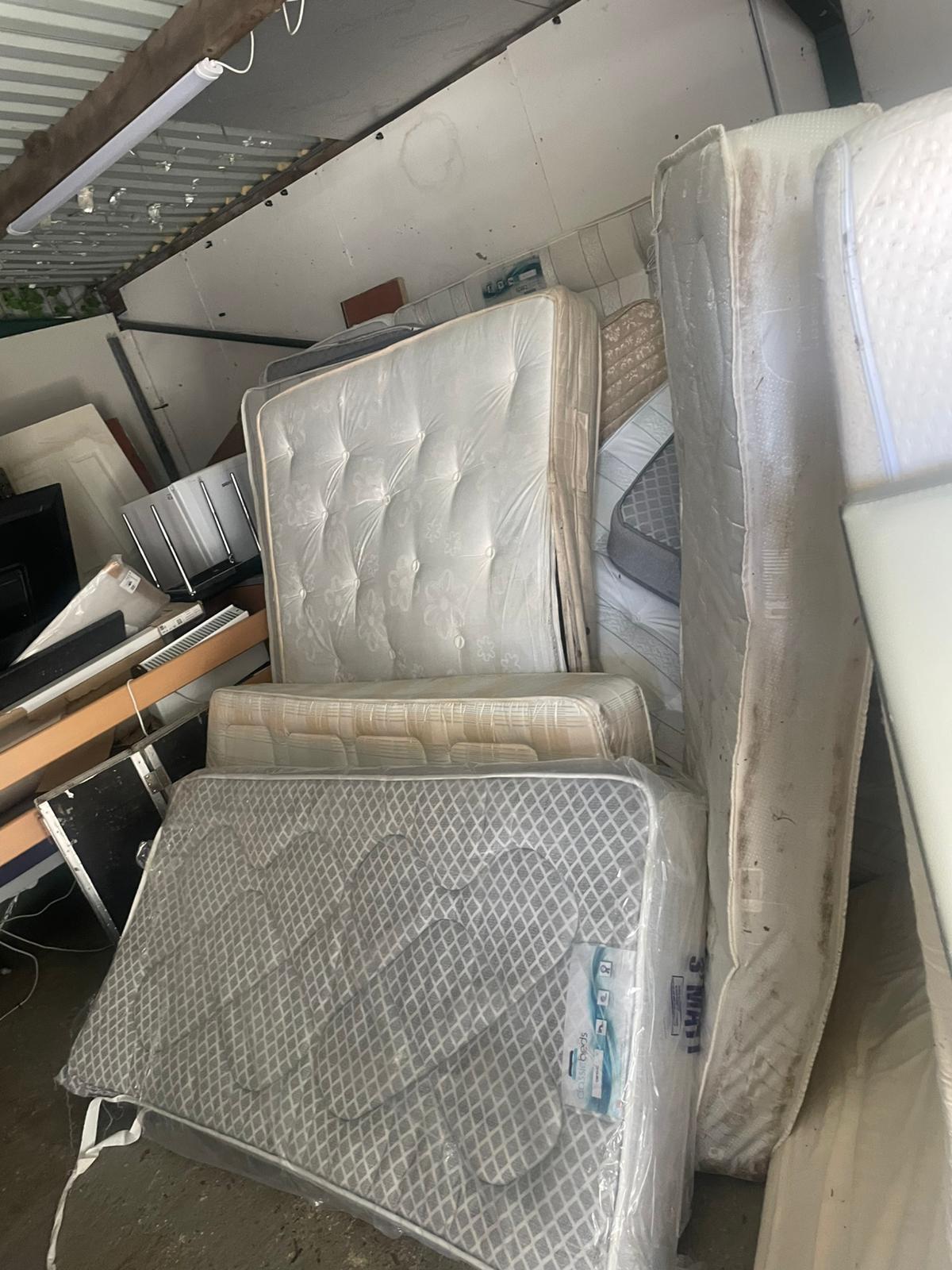 Several old mattresses stacked upright awaiting removal