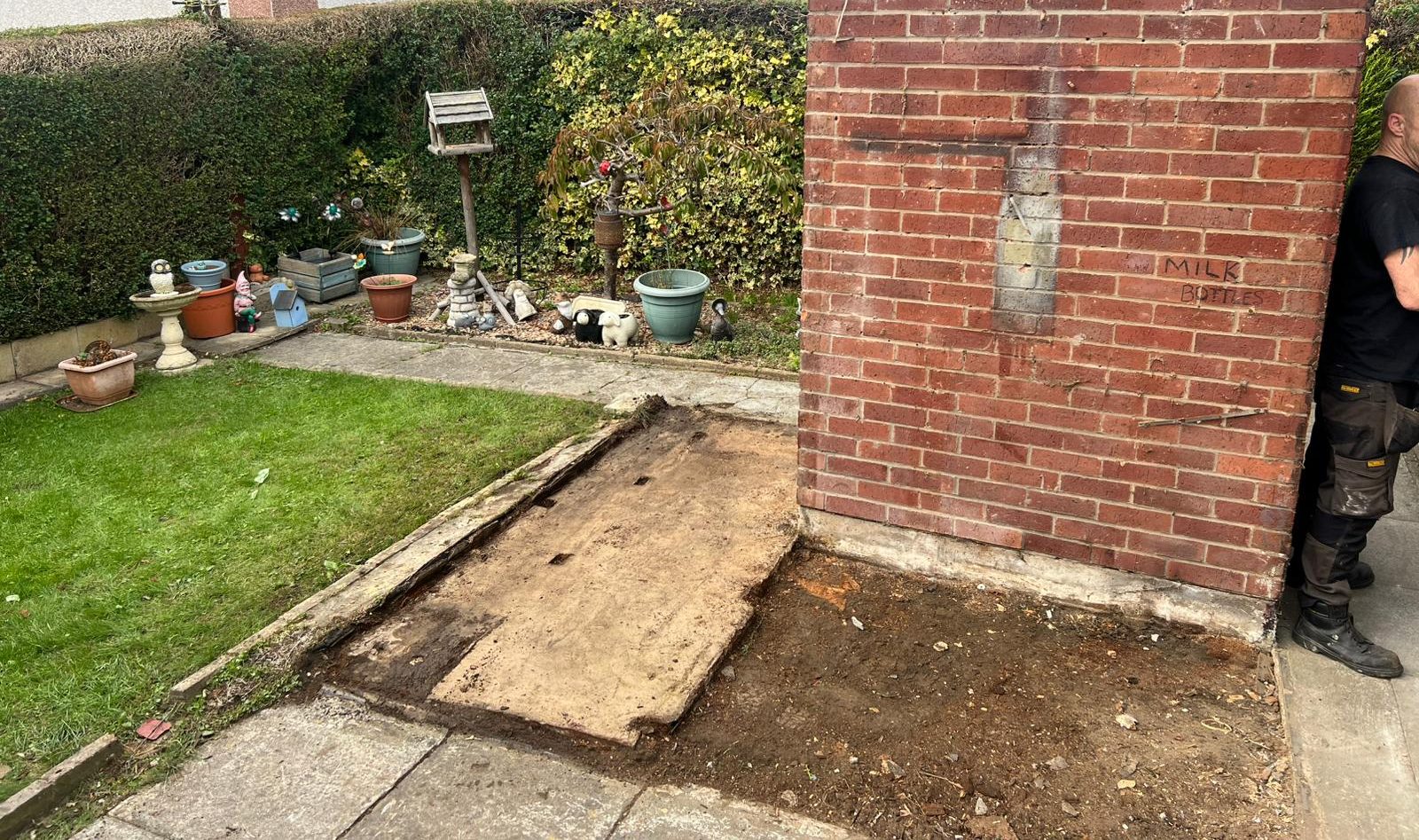 Bare base left after shed removal beside a brick outhouse and lawn