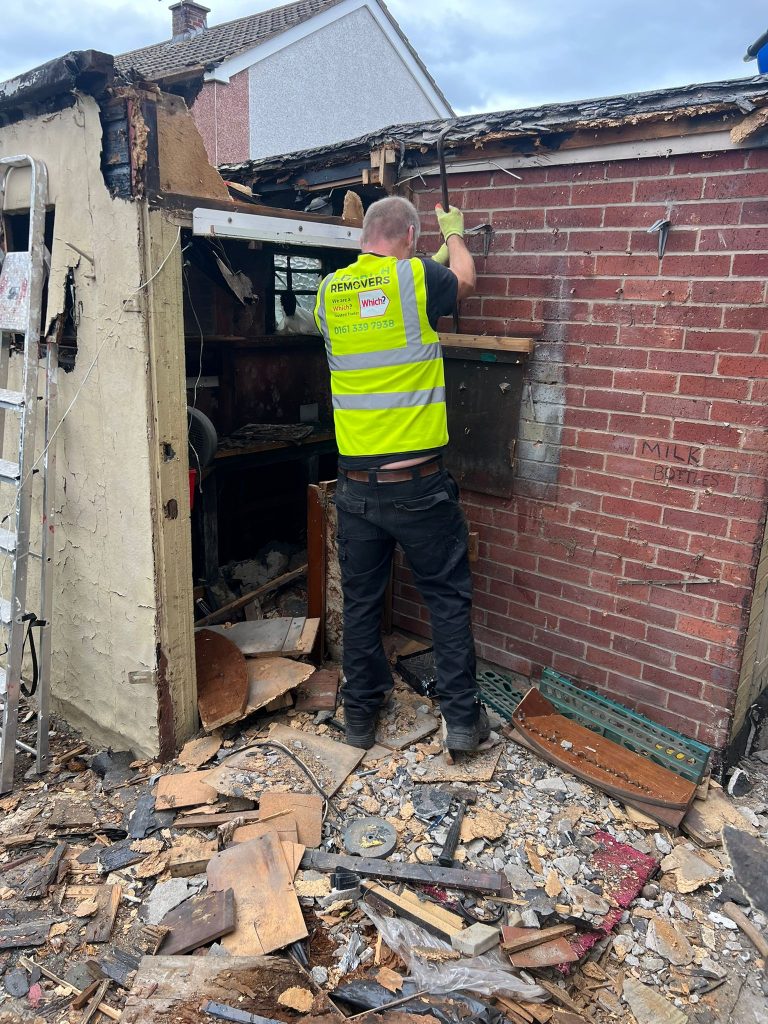 A picture the Rubbish Removers demolishing a large wooden shed in a Tameside garden