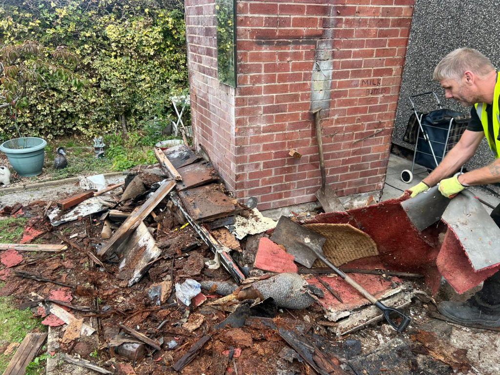 A picture of a Rubbish Removers worker clearing a pile of general waste from a garden.