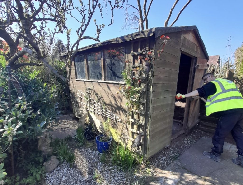 A picture of a Rubbish Removers worker dismantling a large shed in a Tameside garden