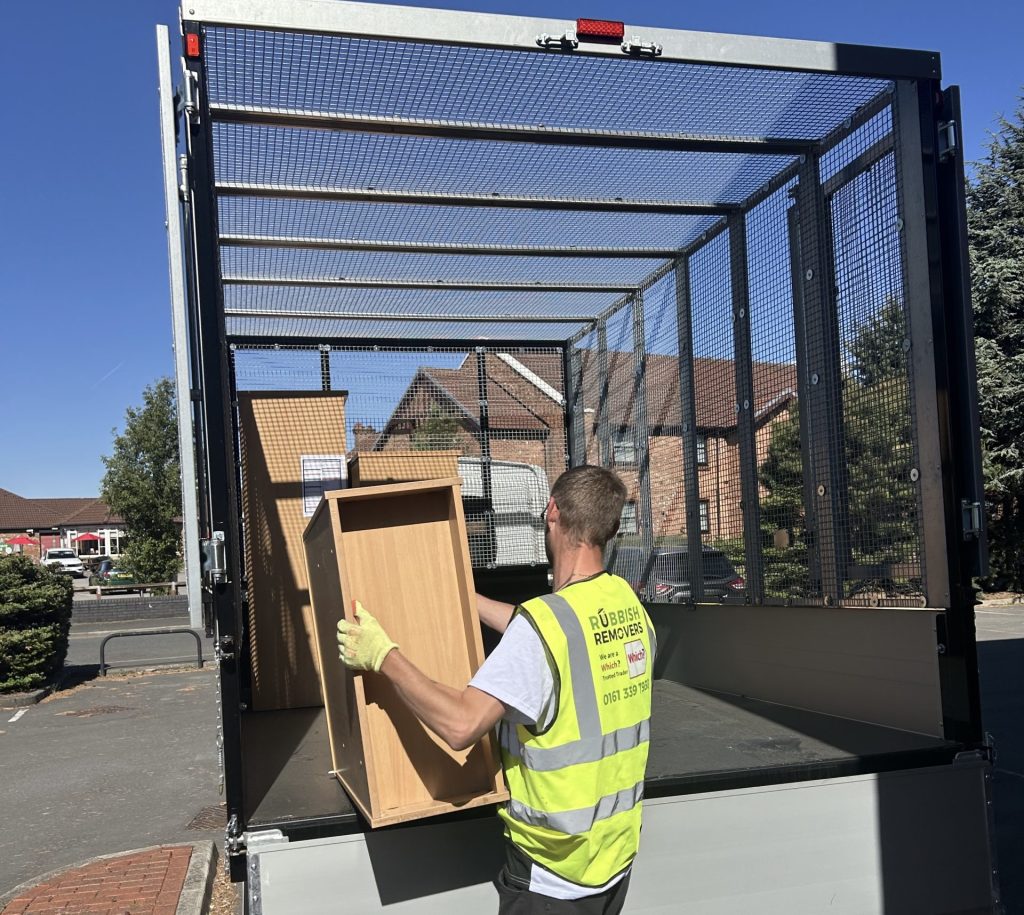 A picture of a rubbish removers worker loading a wooden shelving unit onto a 14-yard cage tipper van.