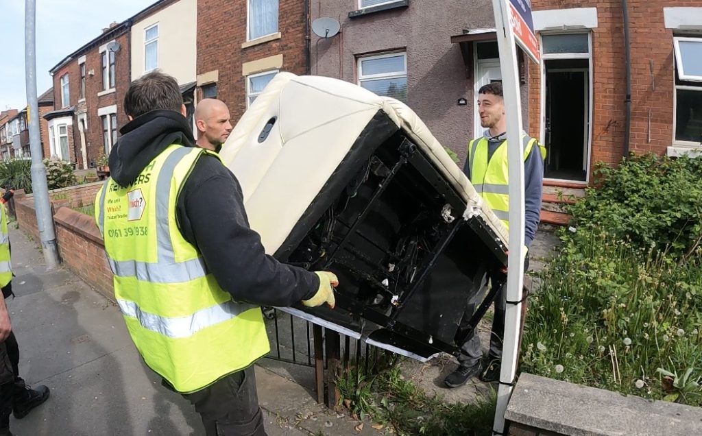 A picture of Rubbish Removers workers carrying a sofa out of a house.