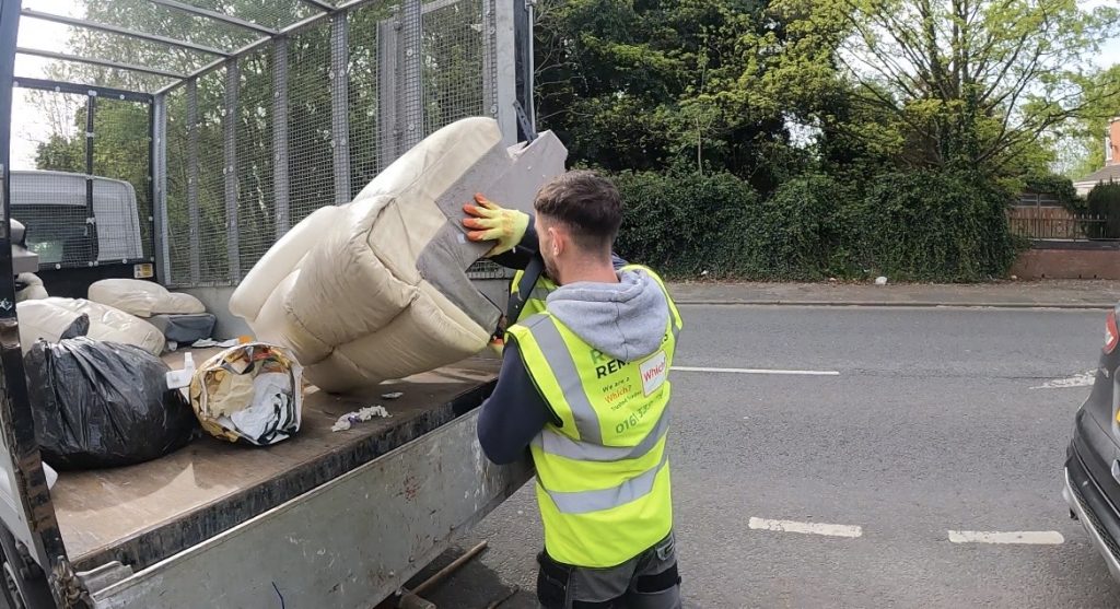 A picture of a Rubbish Removers worker loading a sofa onto a 14-yard cage tipper van.