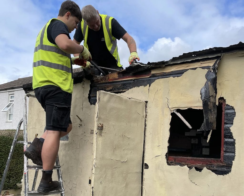 Two man team dismantling an old outbuilding from a customers garden