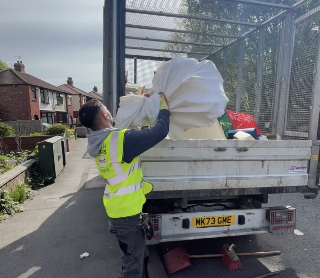 Image of team member loading rubbish onto the vehicle from a clearance.