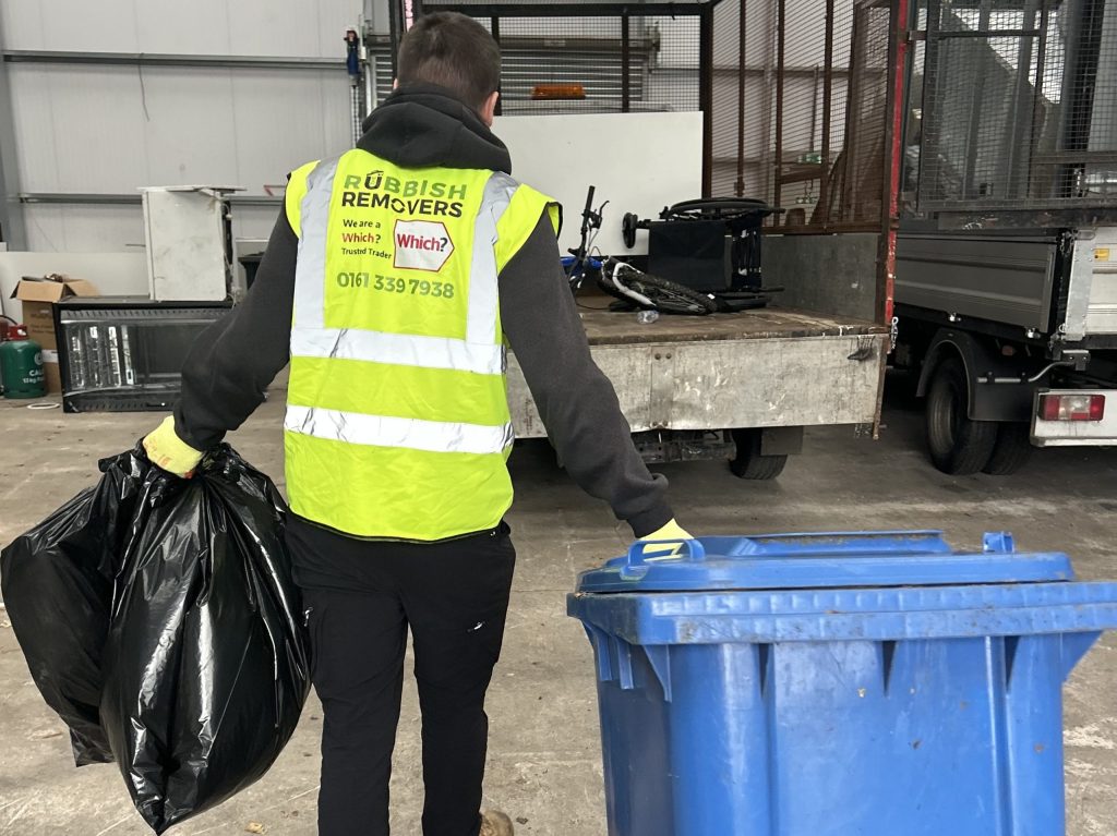 Uniformed team member loading bin waste and bagged waste onto the van