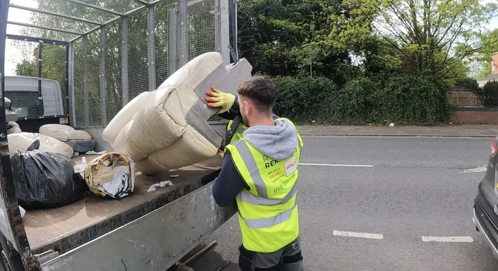 Image of staff member loading a dismantled sofa onto the vehicle ready for disposal.