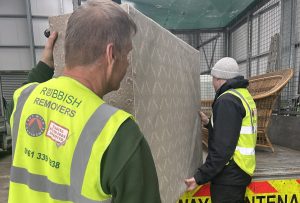 Two staff members loading a mattress onto the vehicle.