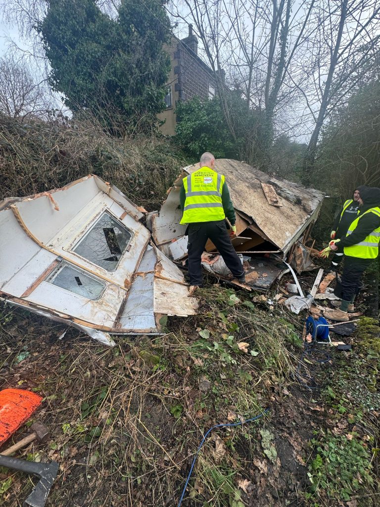 Image of staff clearing fly tipped waste from a country lane.