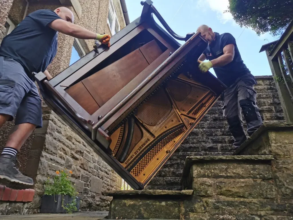 Staff members removing a piano from a property.