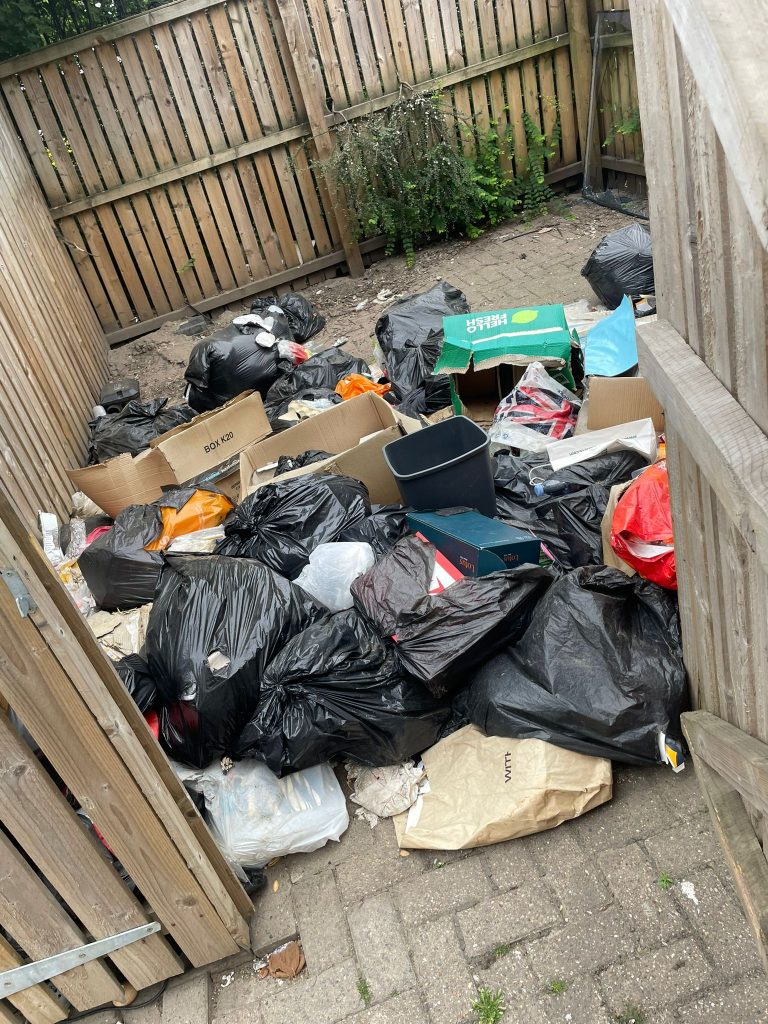 Overflow waste being cleared from around communal bin stores at the Salford tower block