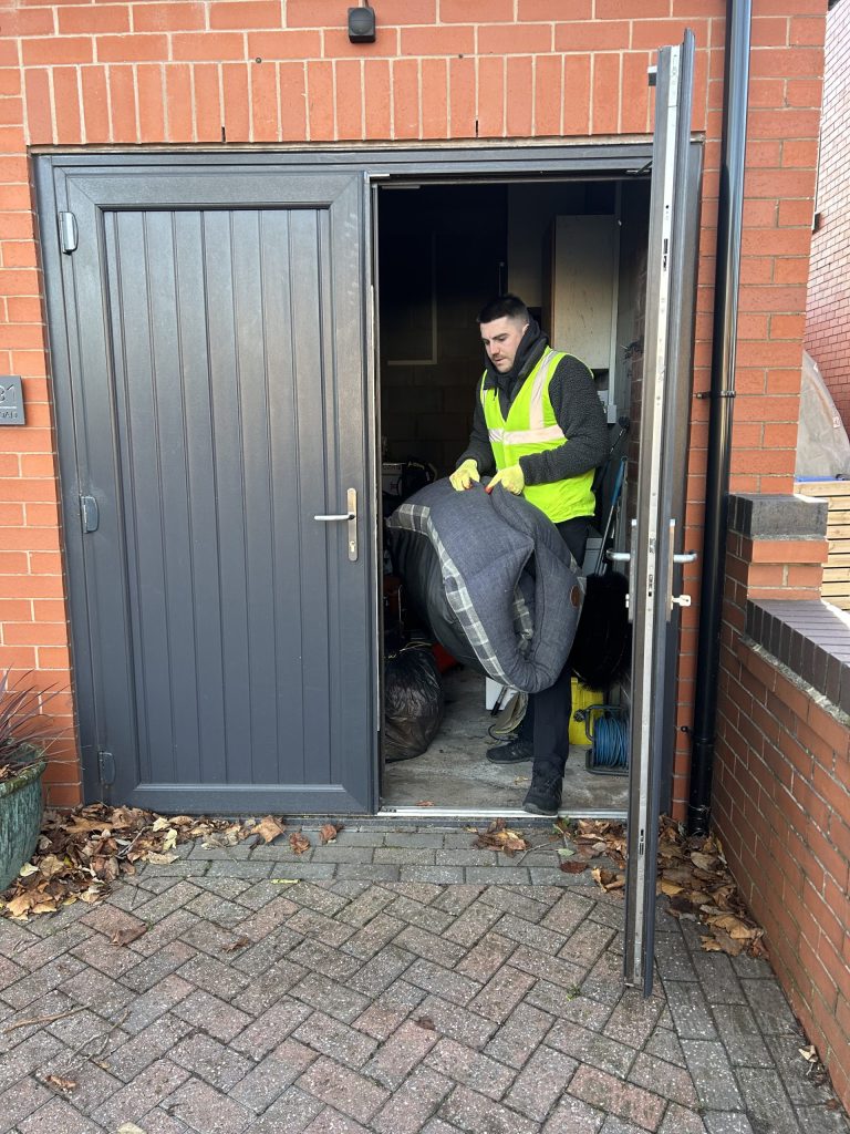Staff member clearing waste from a garage.
