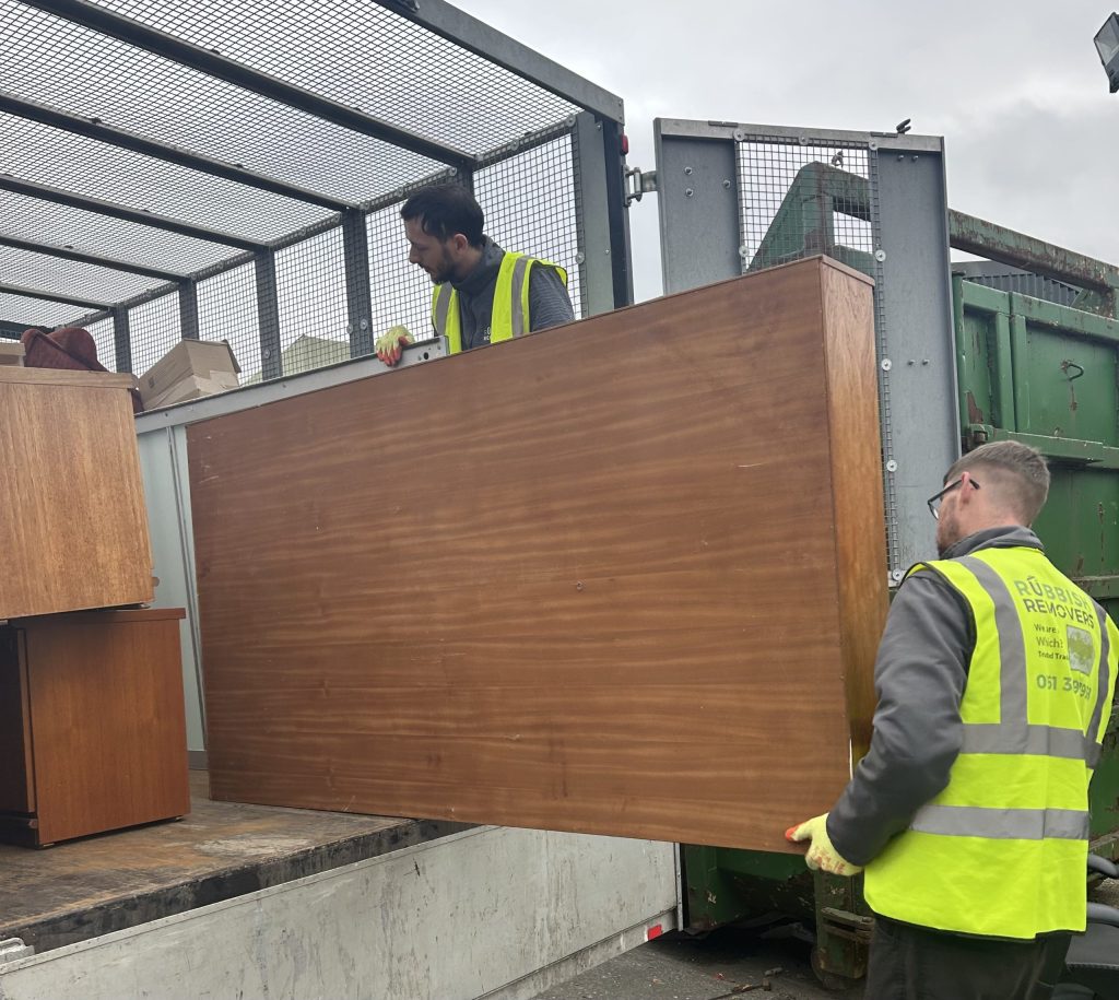Uniformed crew loading large office furniture onto their van