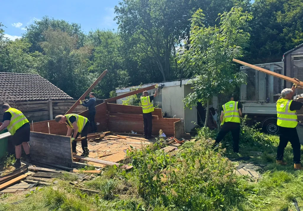 Uniformed teams dismantling an old shed and removing the wood waste
