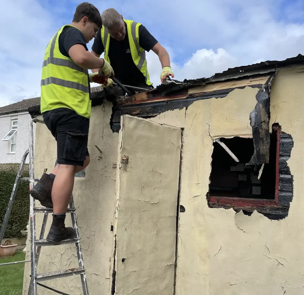 Staff members dismantling a shed for a customer.