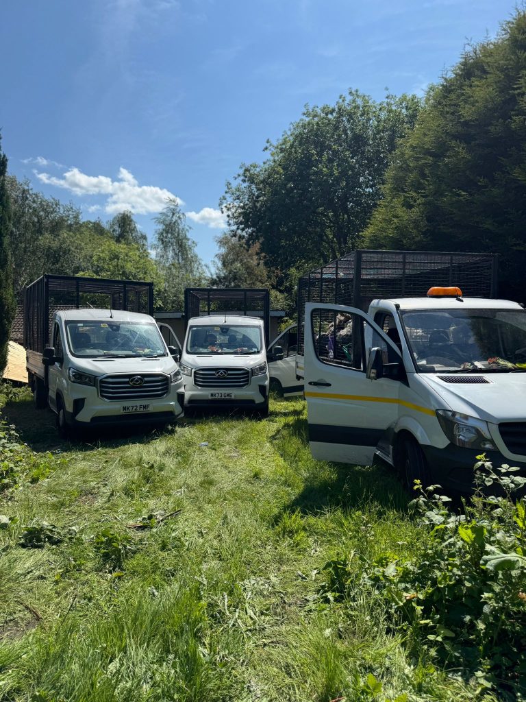 Three caged tipper vehicles positioned close to the waste during a Heywood garden clearance.