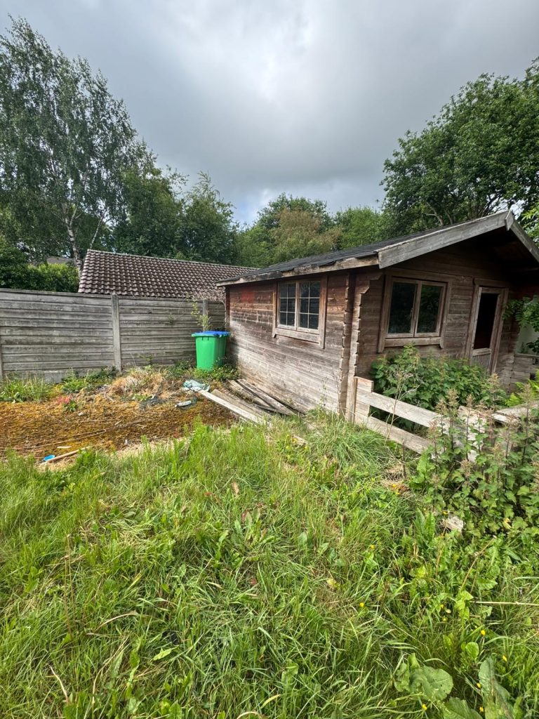 Overgrown garden and outbuildings before clearance in Heywood.